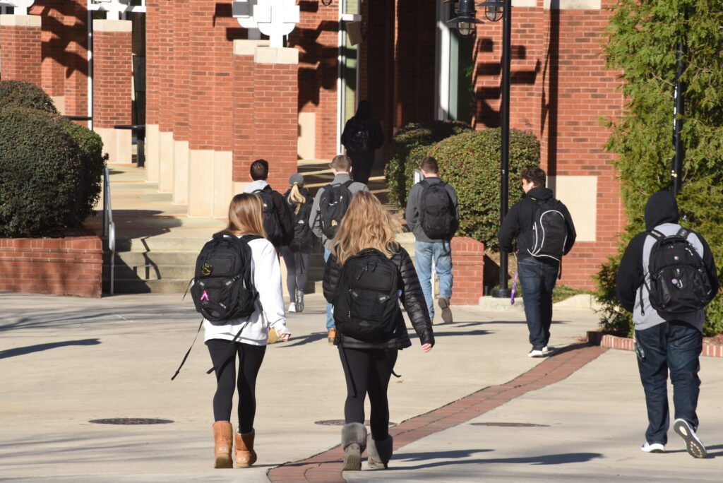 College school students walking with backpacks toward a college campus building